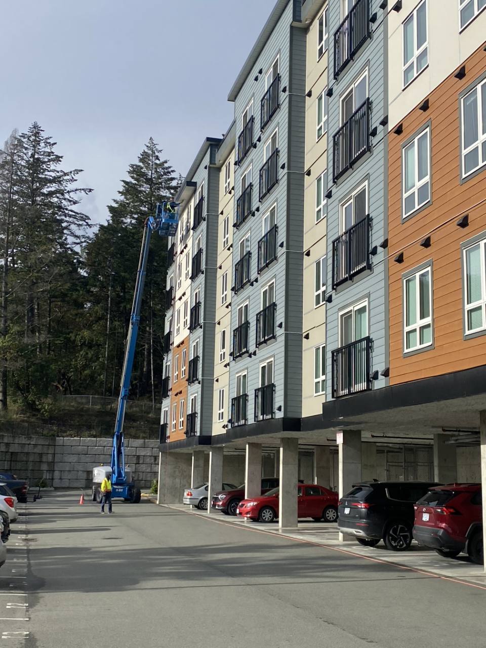 Team using a blue boom lift to service a multi-storey residential building