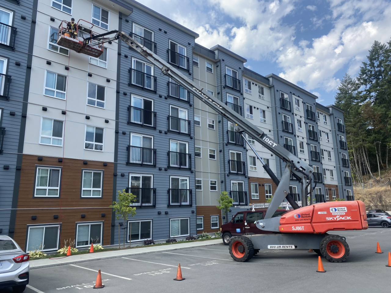 Employee in a boom lift servicing the upper level of a large apartment building