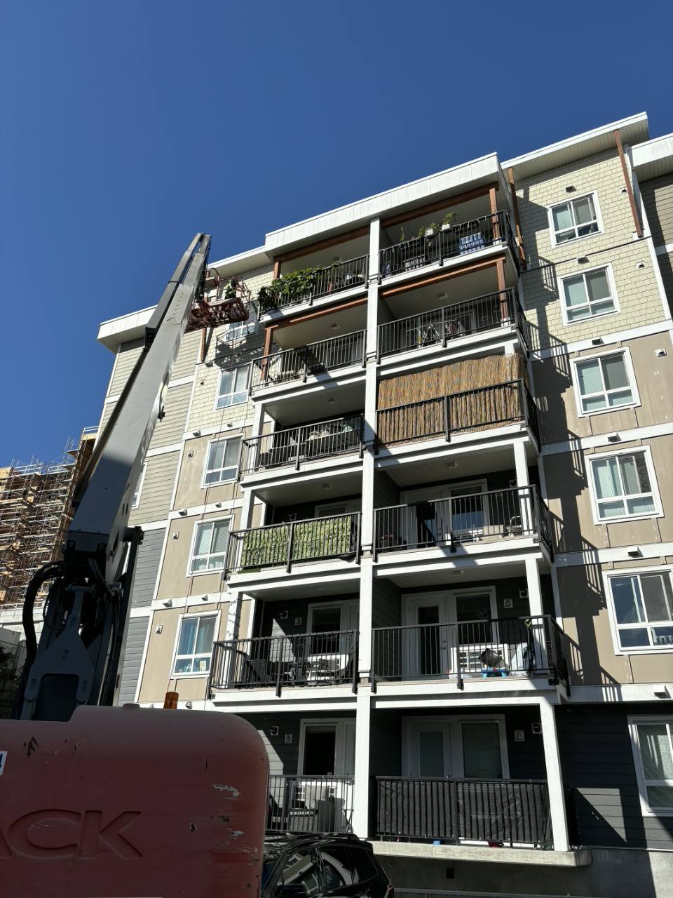 Employee working from a boom lift at the upper floor of an apartment building
