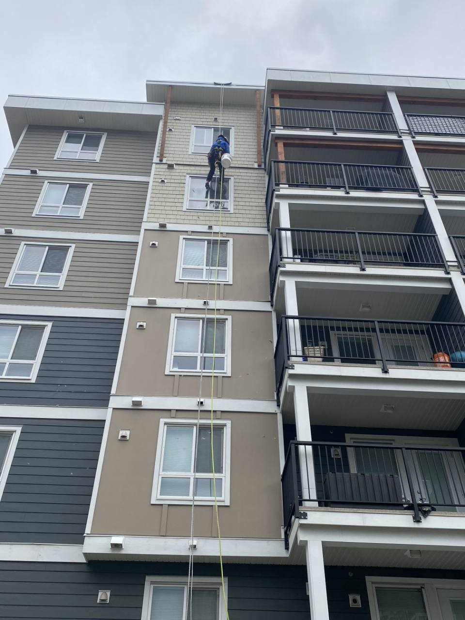 Rope-access employee working on the exterior of a multi-storey apartment building